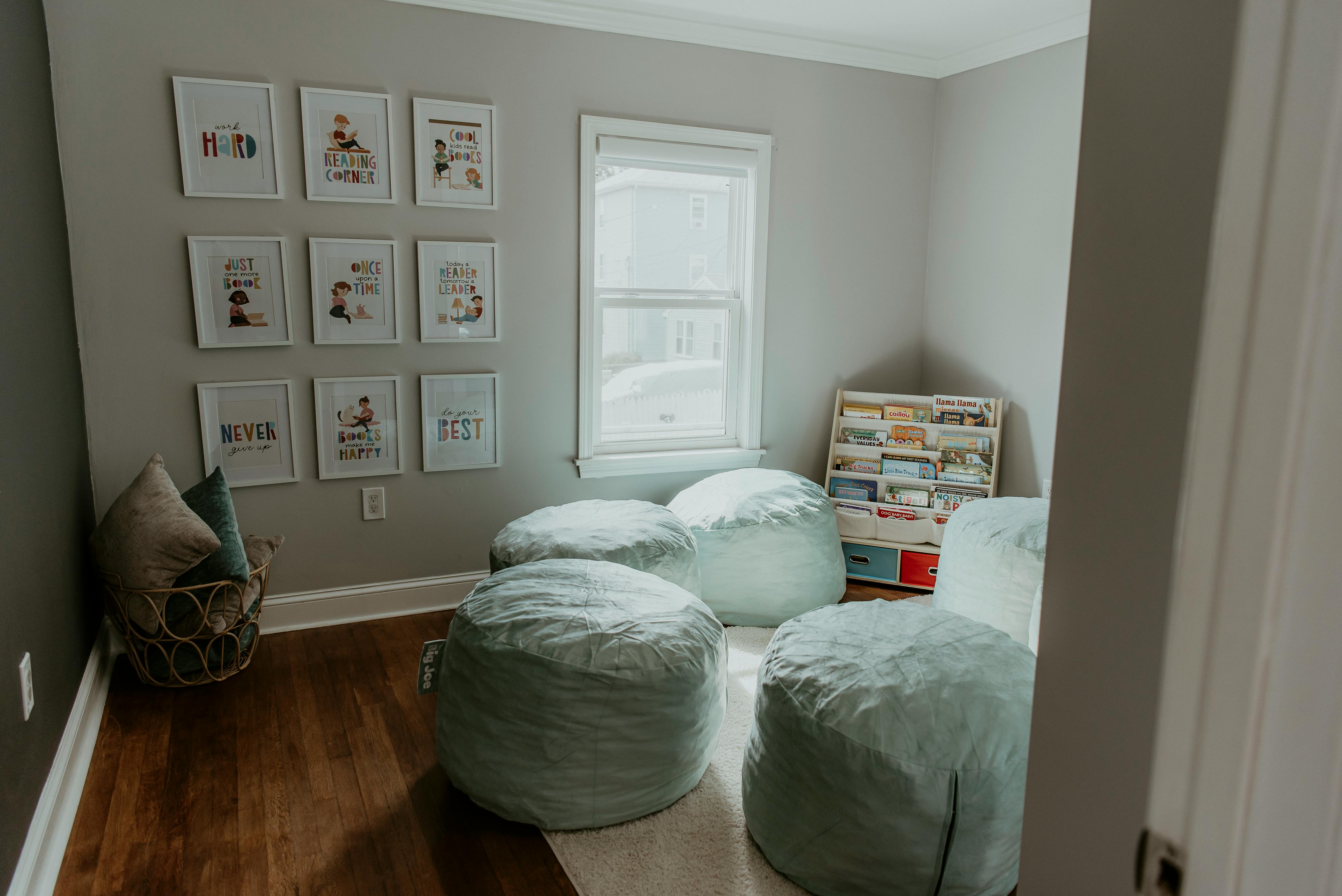 Room with multiple beanbag chairs, framed pictures on wall, and window