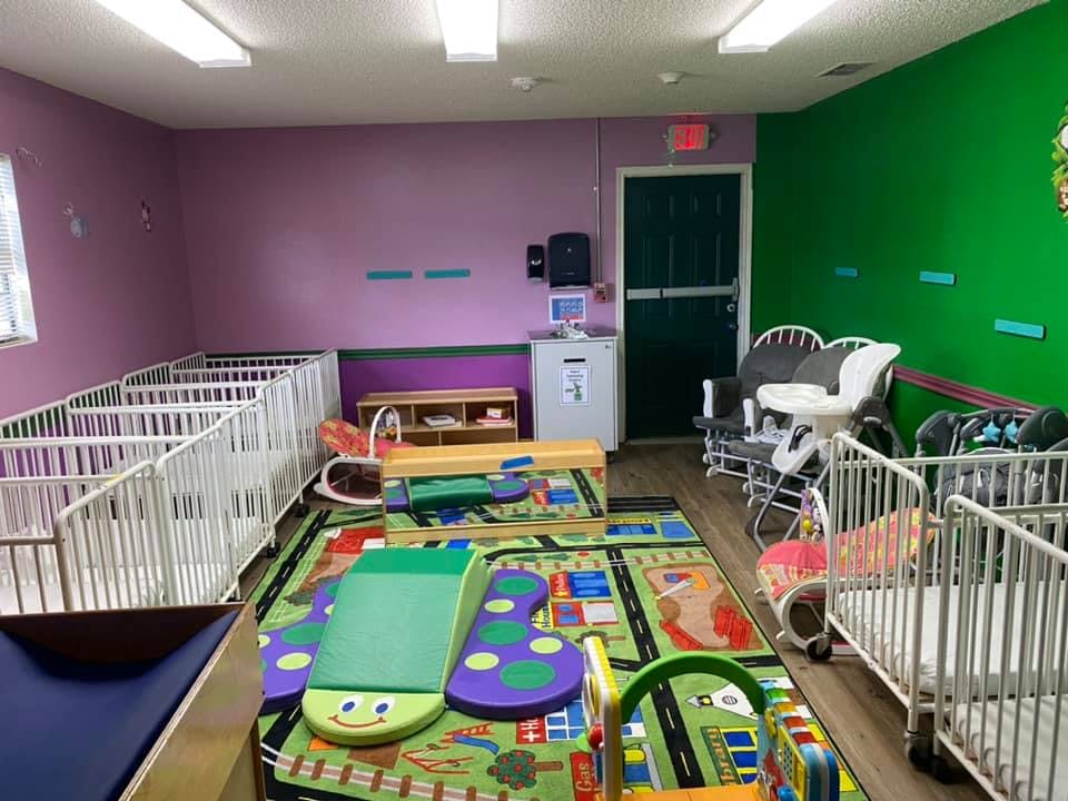 Nursery room with multiple cribs, play mats, and children's furniture