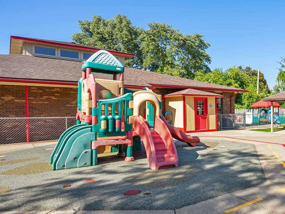Colorful playground structure with slides on soft ground next to a building