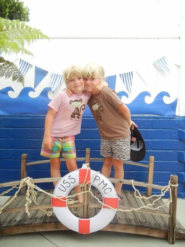Two children embracing on a small wooden bridge with a life preserver