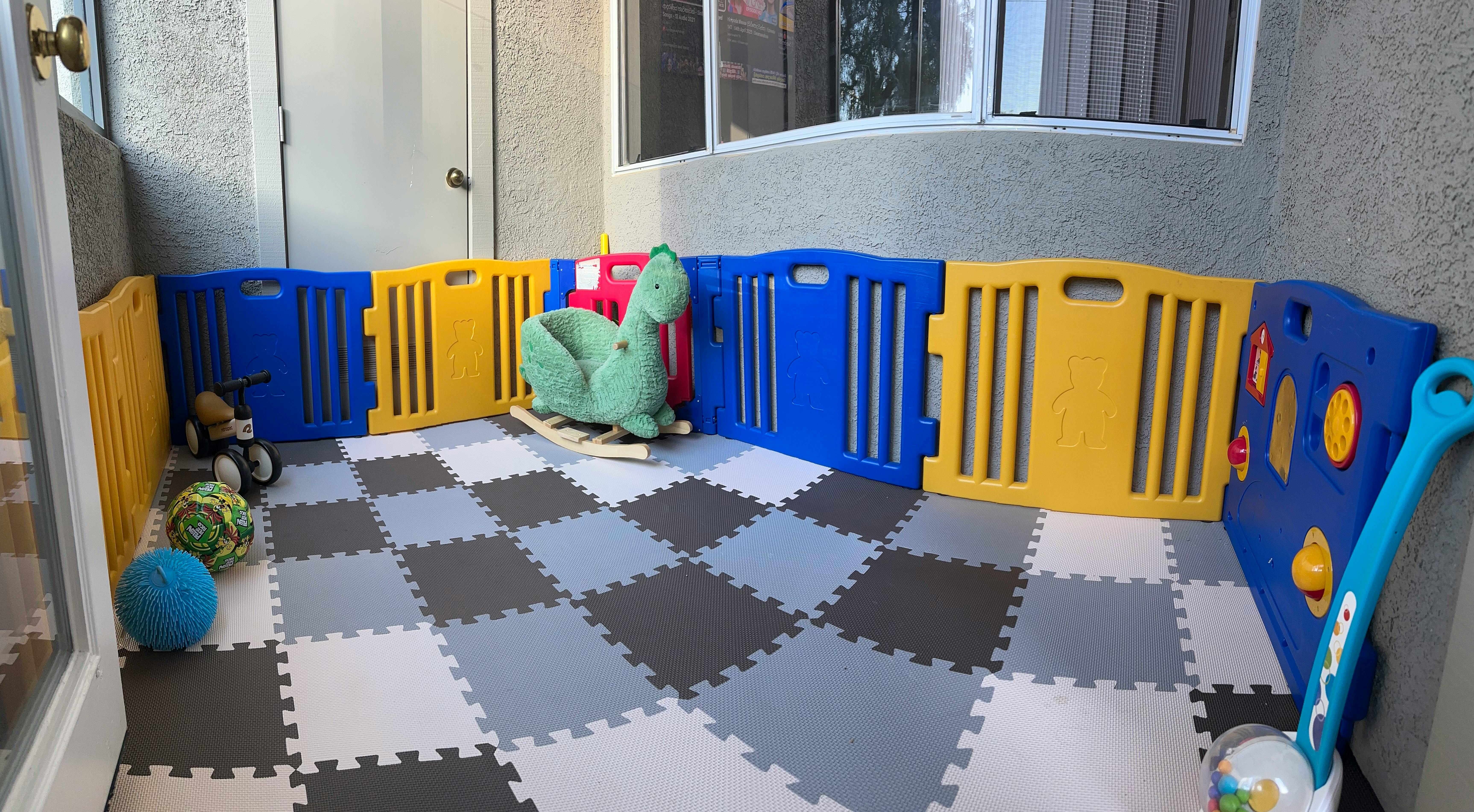 Play area with colorful interlocking floor mats and a playpen