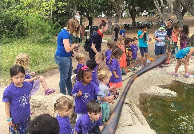 Adults and children gathered around a body of water outdoors
