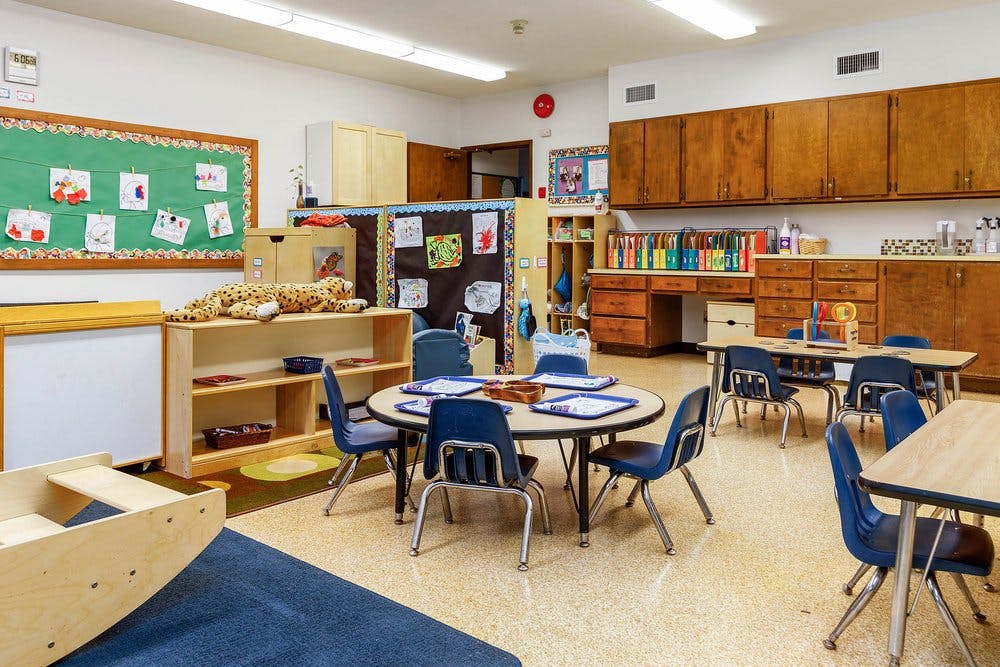 Empty colorful preschool classroom with small tables and chairs