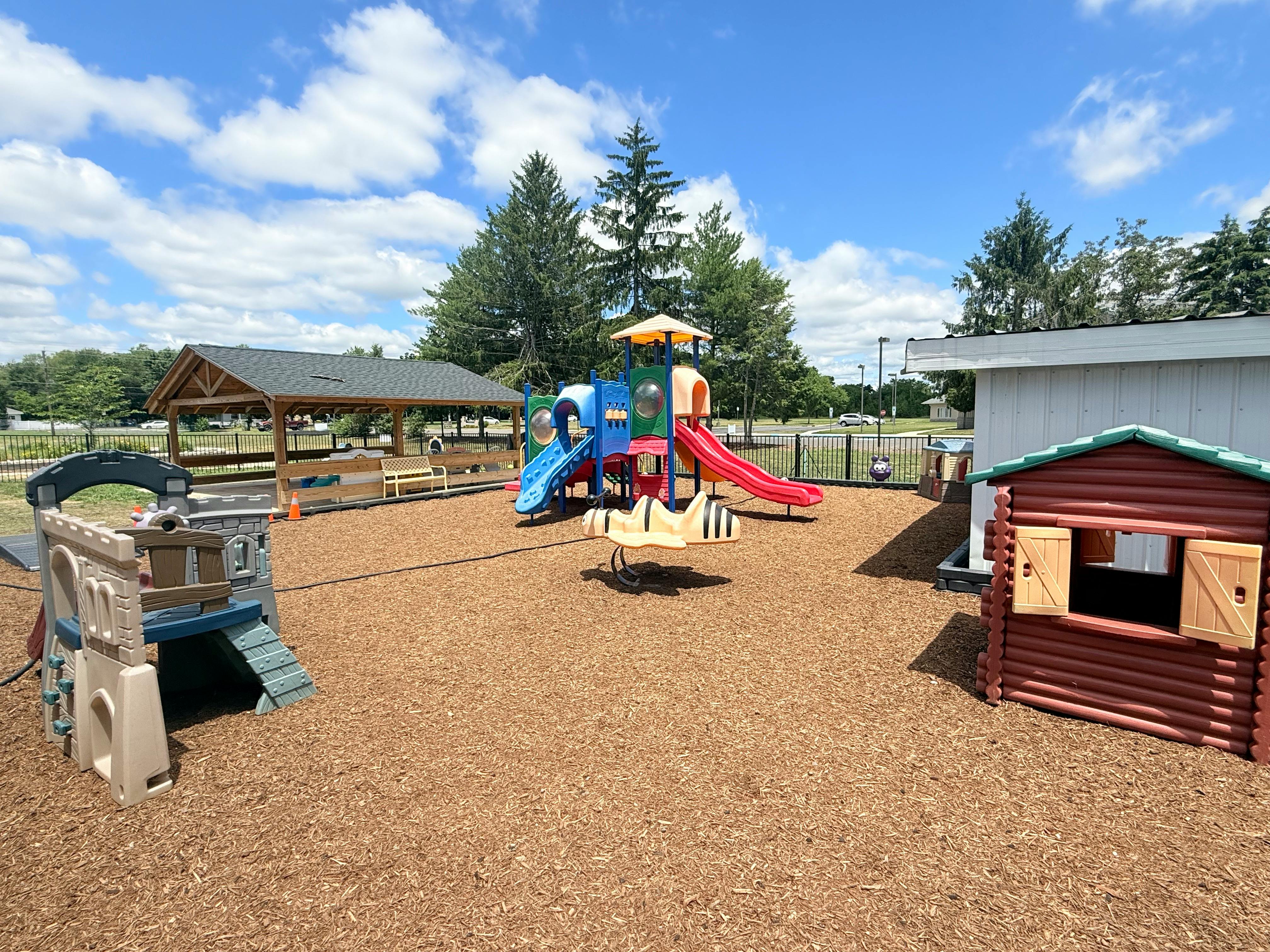 Playground equipment including slides and small play houses on wood mulch