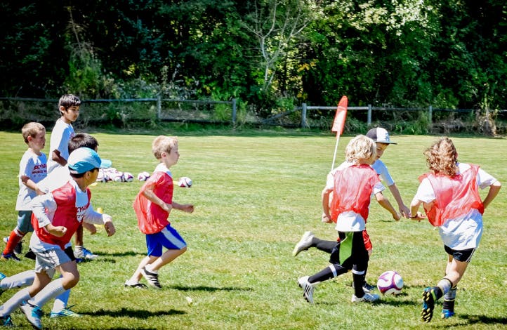 Children playing soccer on a grassy field