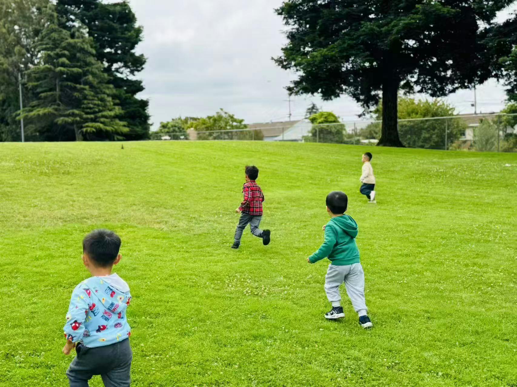 Four children running on a grassy field