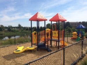 Playground structure with slides and climbing areas next to a body of water