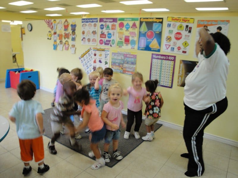 Adult leading a group of children in an activity in a classroom