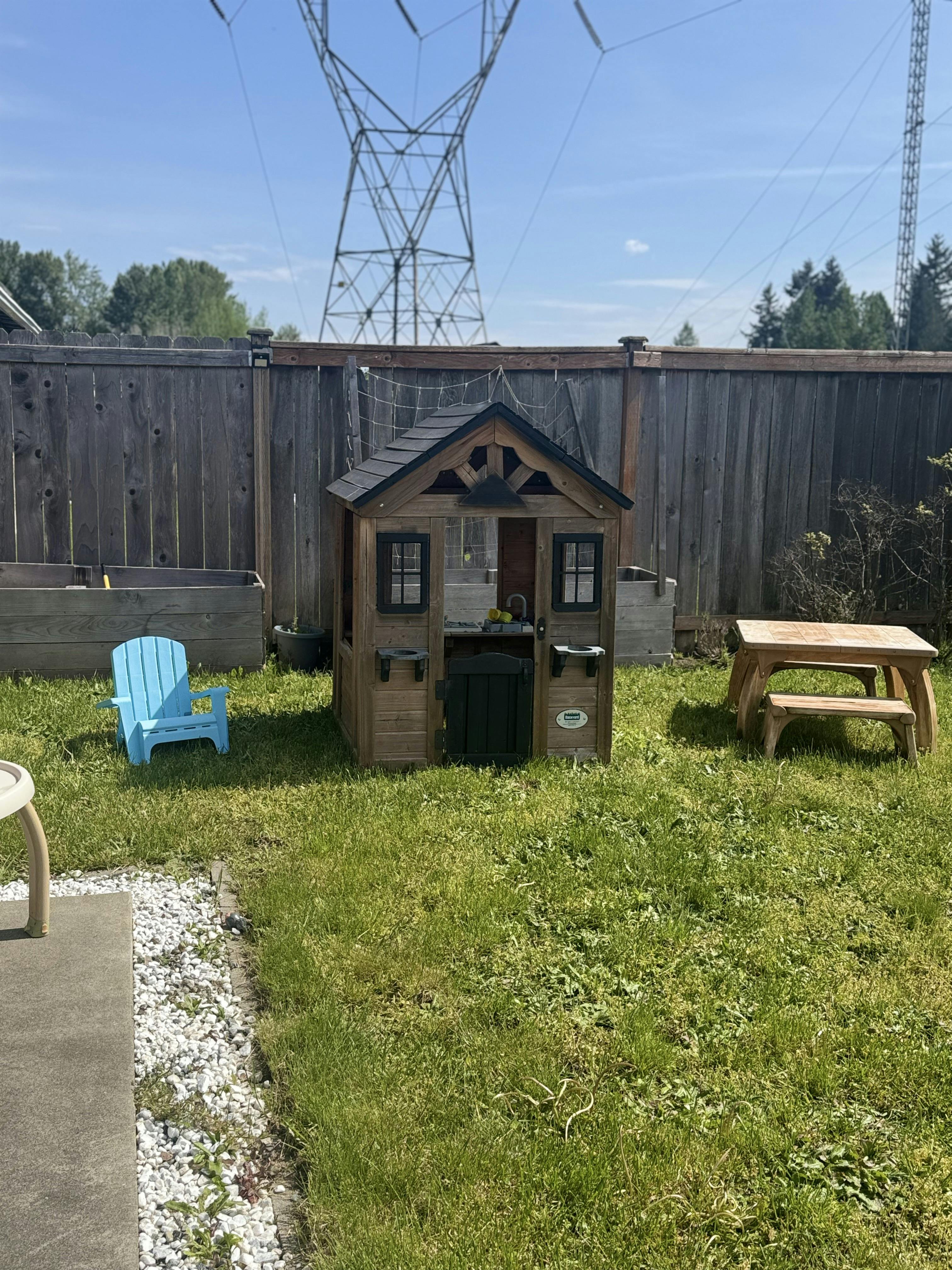 Child's playhouse, blue chair, and picnic table on grass