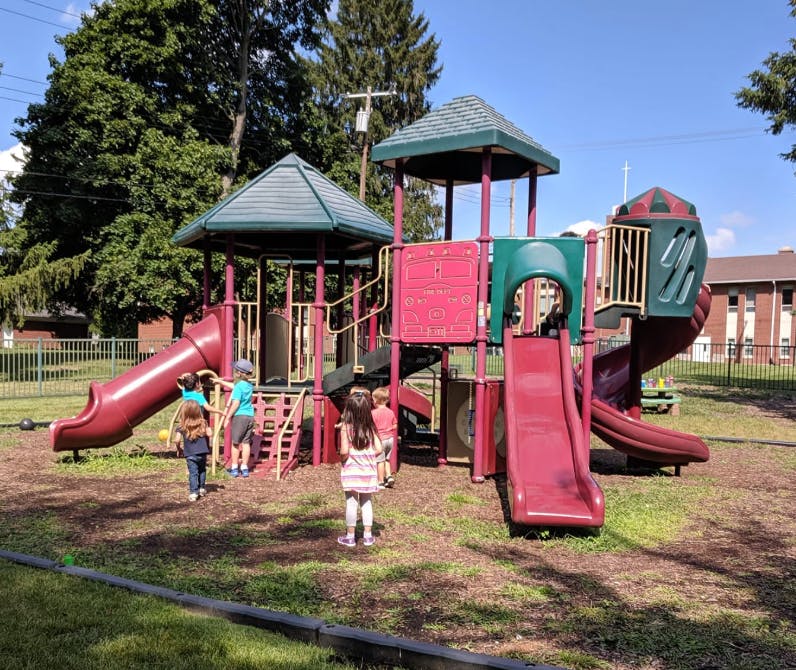 Children playing on a red and green playground structure