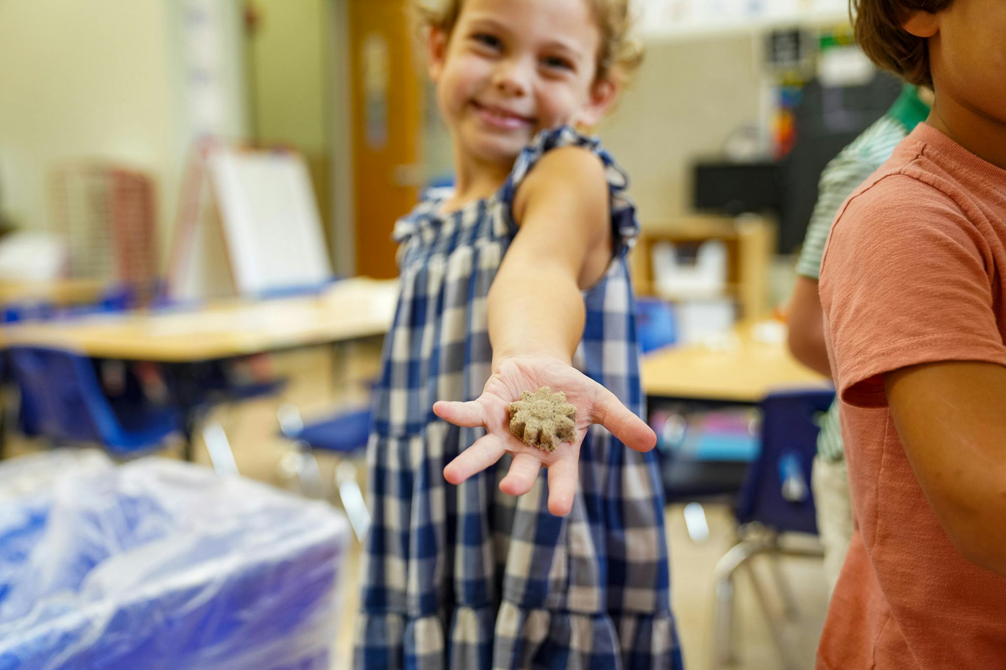 Child holding a small object in an outstretched hand