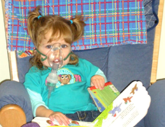 Child wearing a medical mask and holding an open book