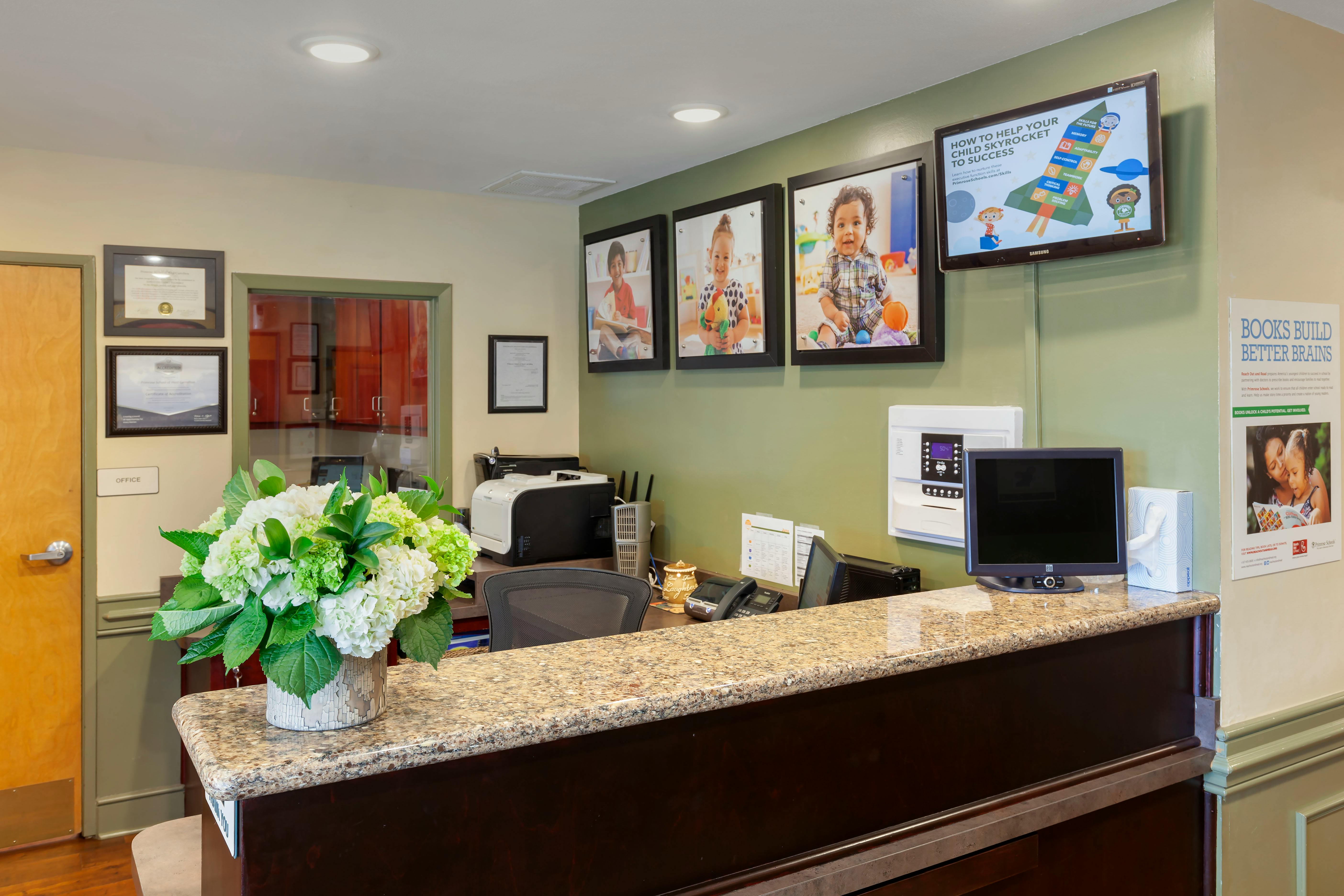 Reception desk with a flower arrangement and baby photos on the wall