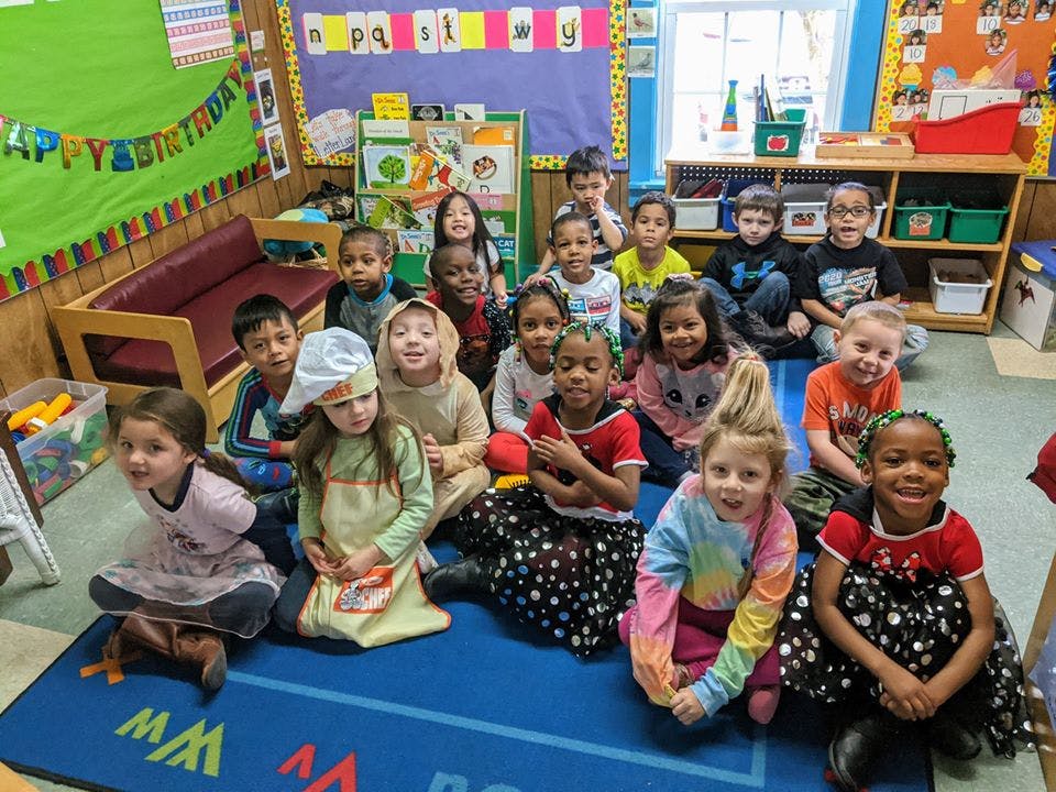 Group of children sitting on a blue rug in a classroom