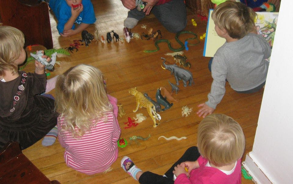 Children playing with animal toys on a wooden floor