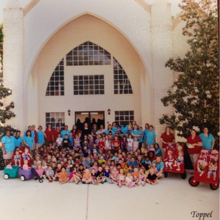 Large group of children and adults posing in front of a building