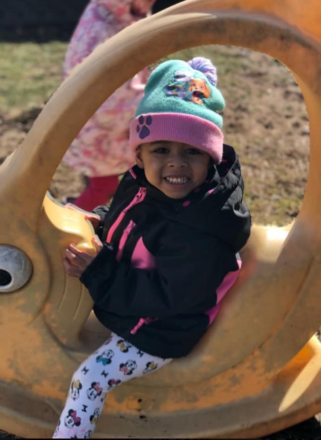 Child in a winter hat and jacket sitting on a playground toy