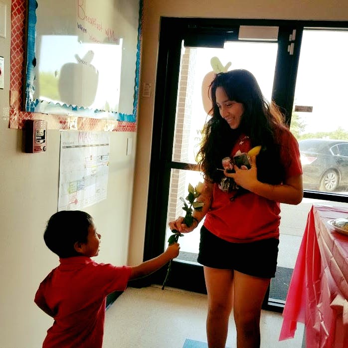 Child giving a flower to a person