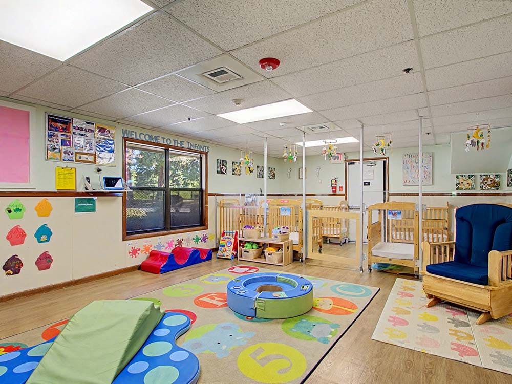Infant nursery room with cribs, play mats, and a rocking chair, text Welcome to the Infants