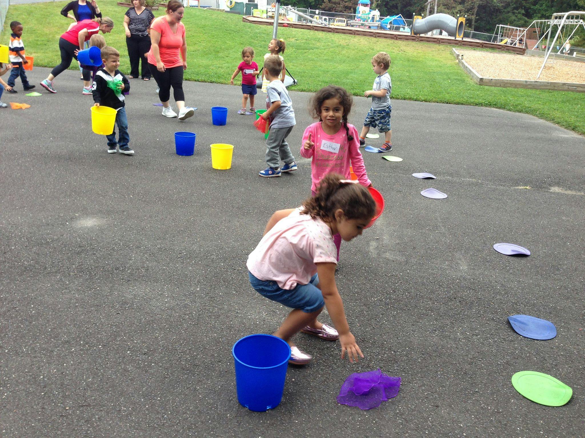 Children playing with buckets and colorful markers on pavement
