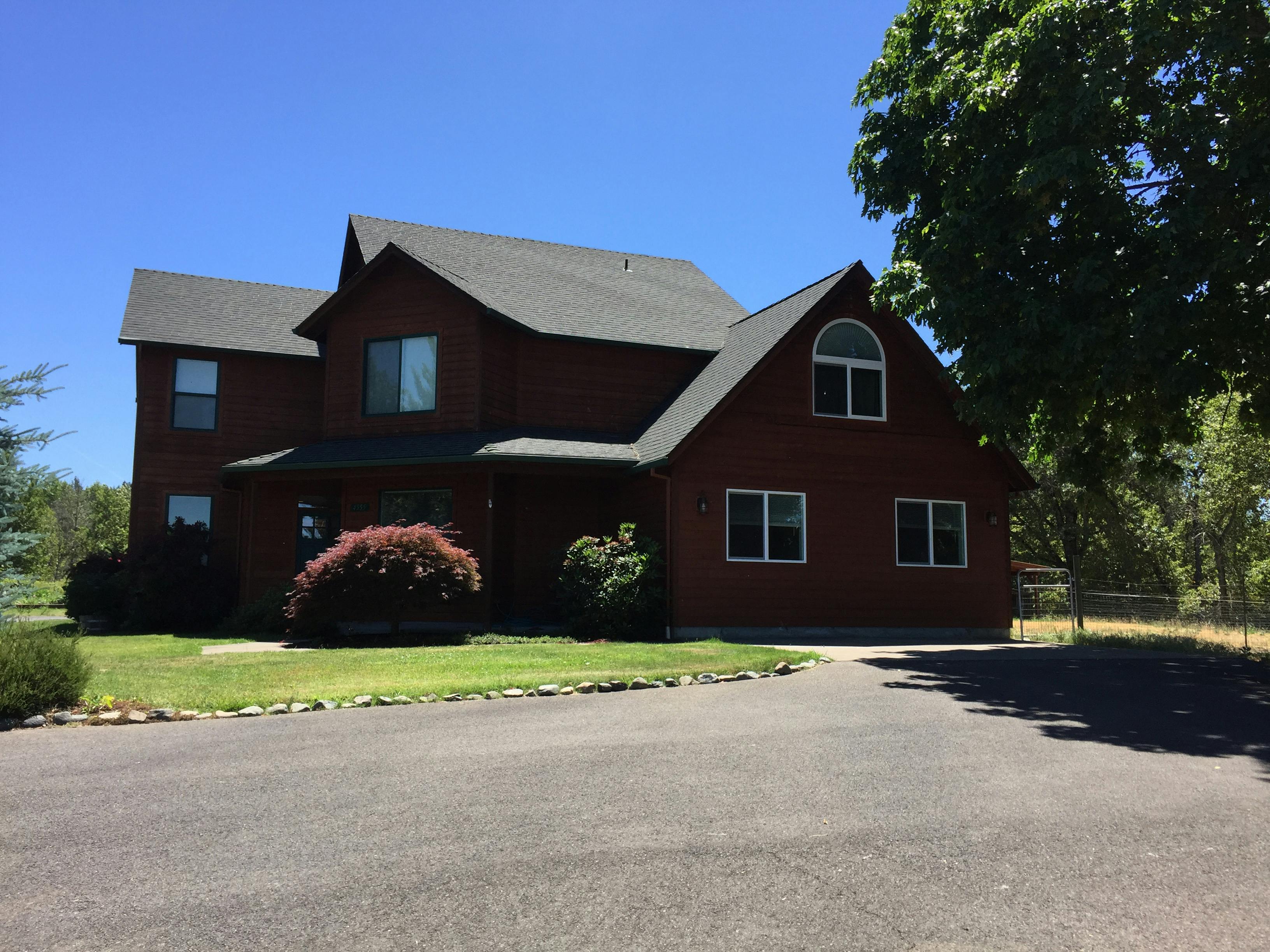 Large house with dark red siding and a dark roof