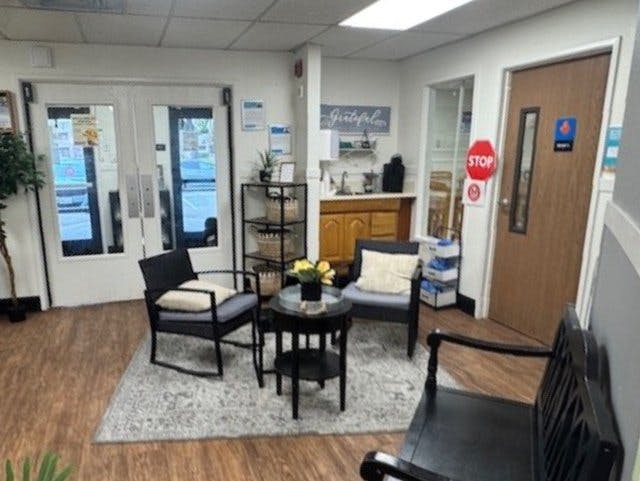 Lounge area with chairs, a small table, and a kitchenette in the background