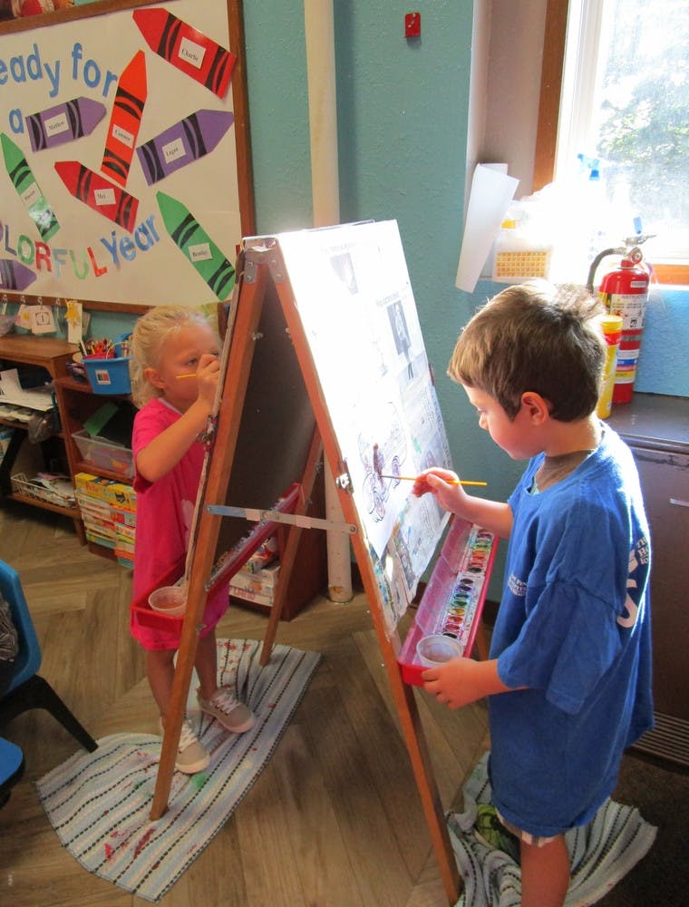 Two children painting at an easel in a classroom