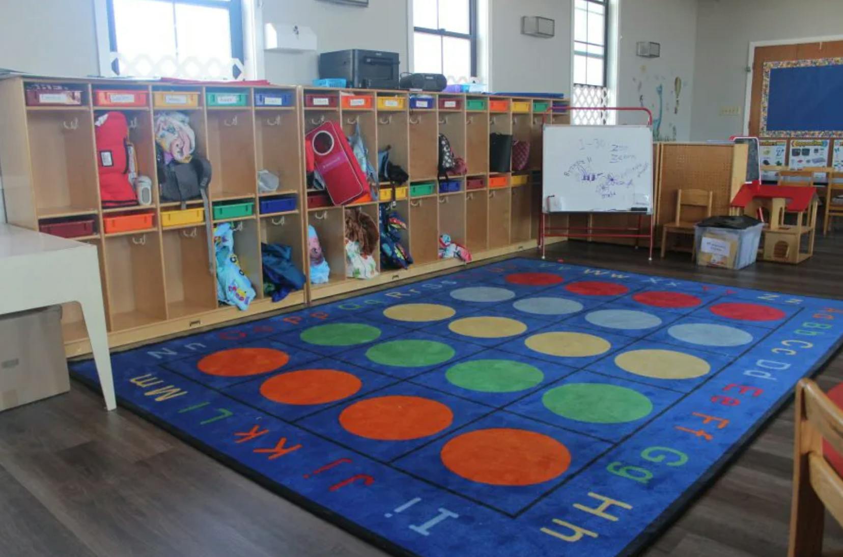Classroom interior featuring cubbies and a colorful alphabet floor rug