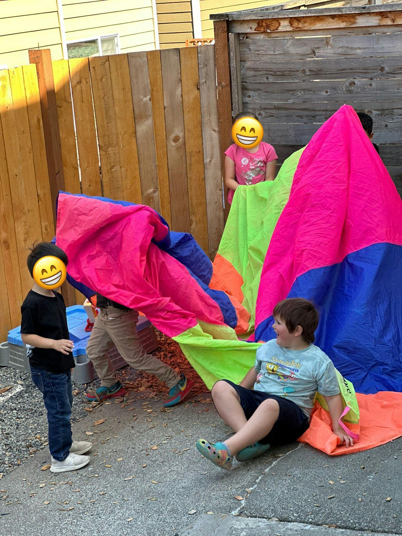 Children playing with a colorful parachute outdoors
