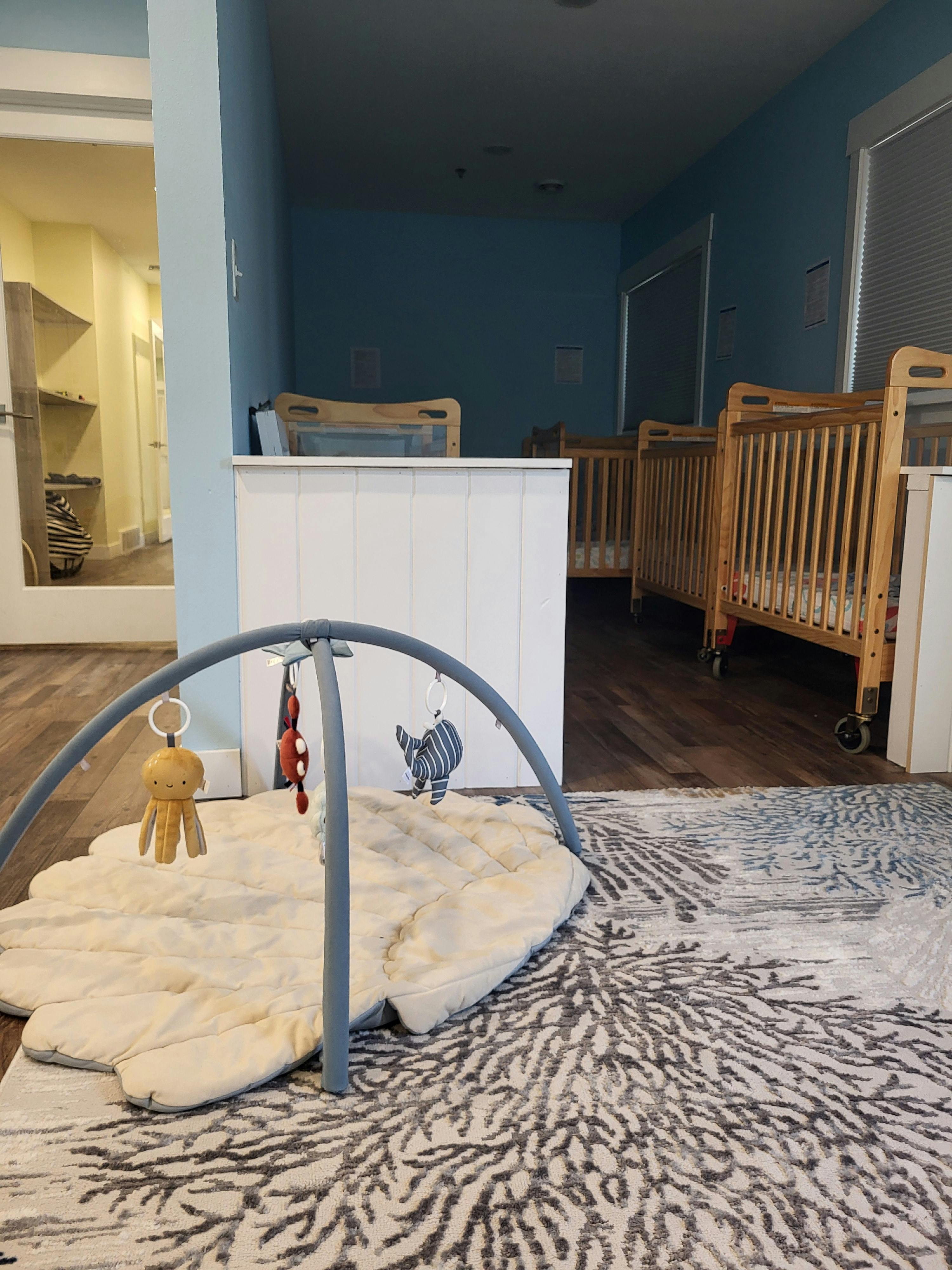 Baby playmat with toys below cribs in a daycare