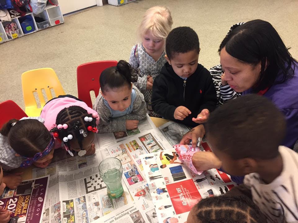 Adult and children gathered around a table covered with newspaper