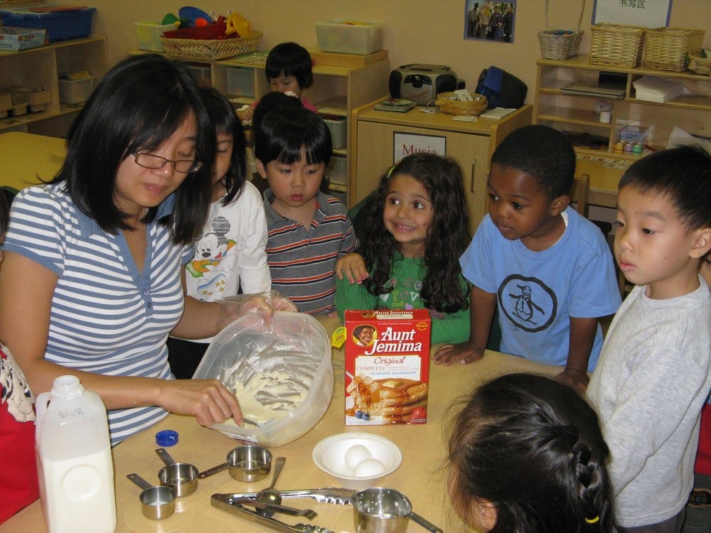 Person mixing batter with children watching in a classroom