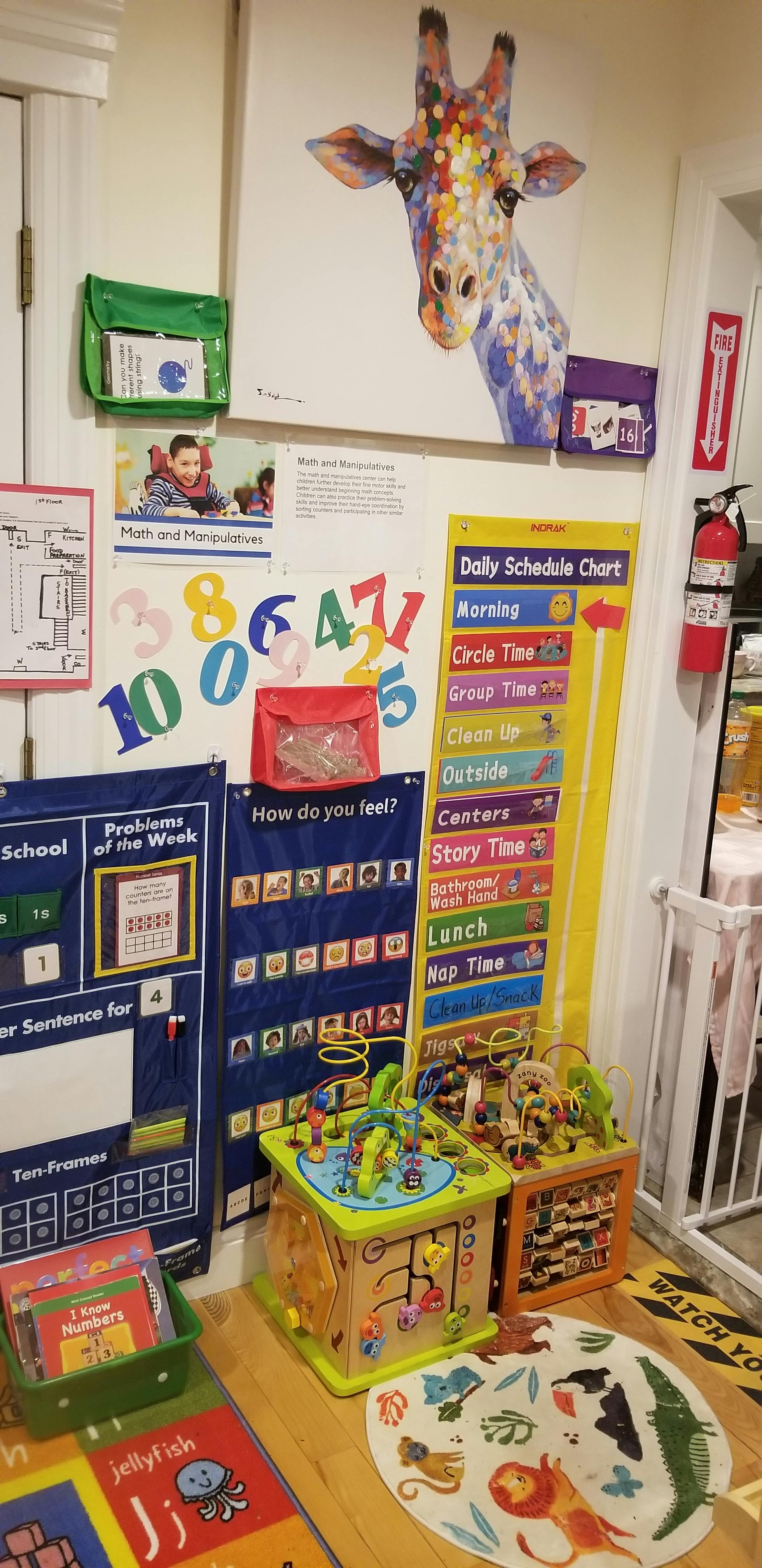 Classroom wall with a giraffe painting, schedule chart, and learning materials