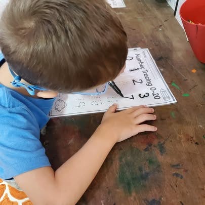 Child tracing numbers on a worksheet