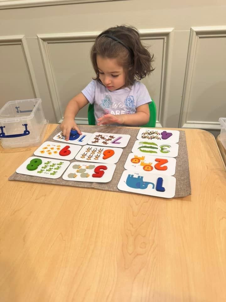 Child playing with number cards on a table