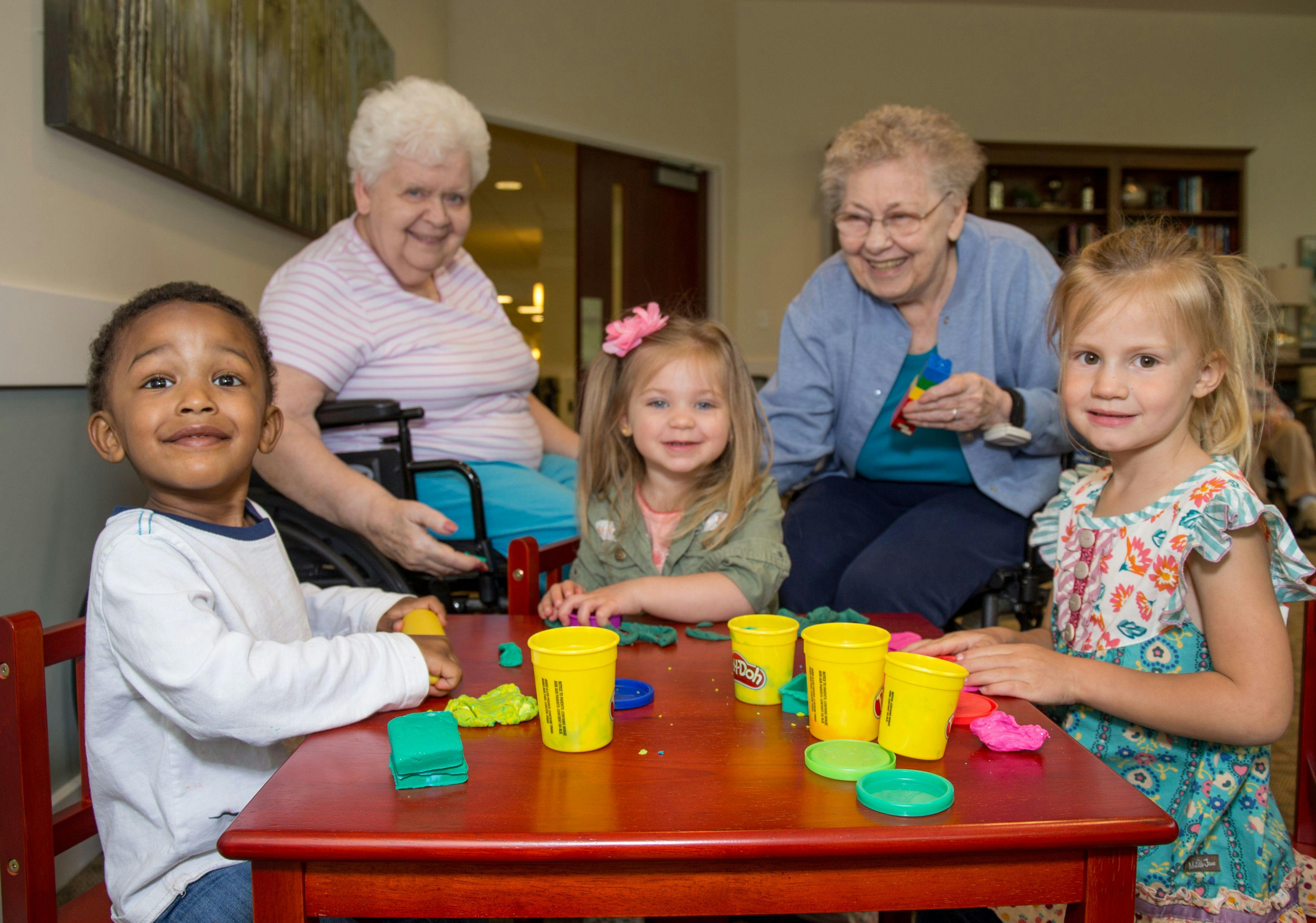 Two adults and three children playing with modeling clay at a table