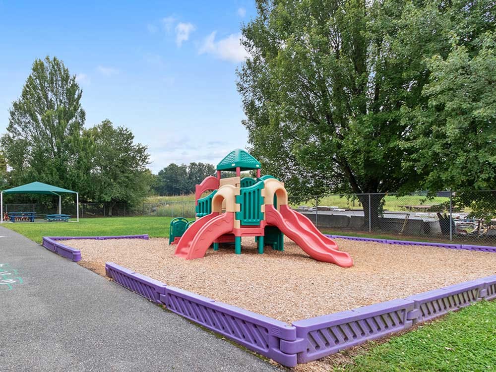 Colorful playground structure on wood chips surrounded by grass and trees