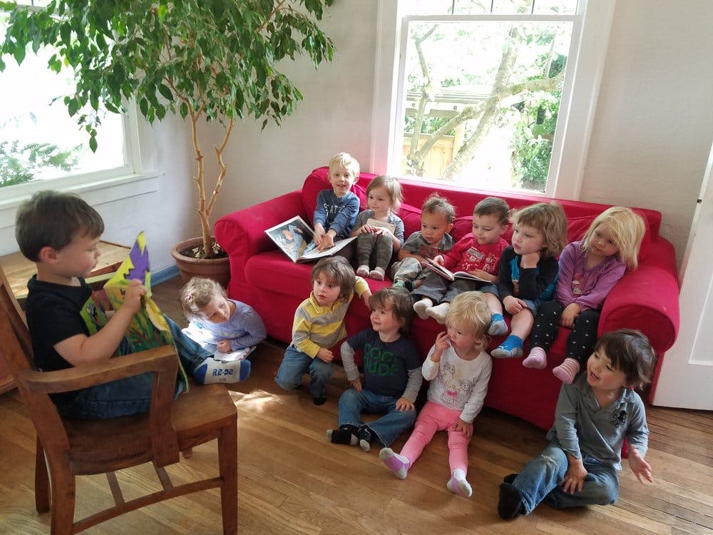 Child sitting in a chair reading to a group of children