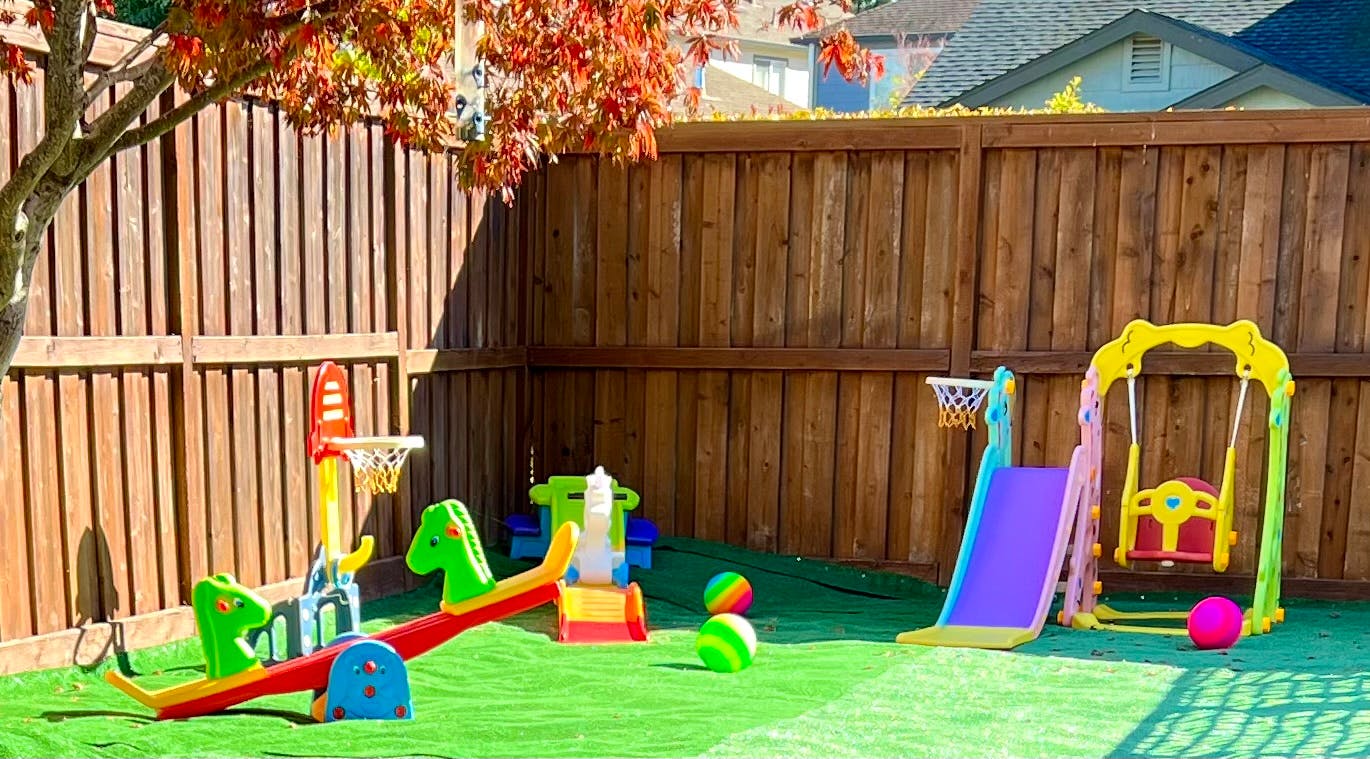 Playground with a slide, swing, and seesaw on artificial turf