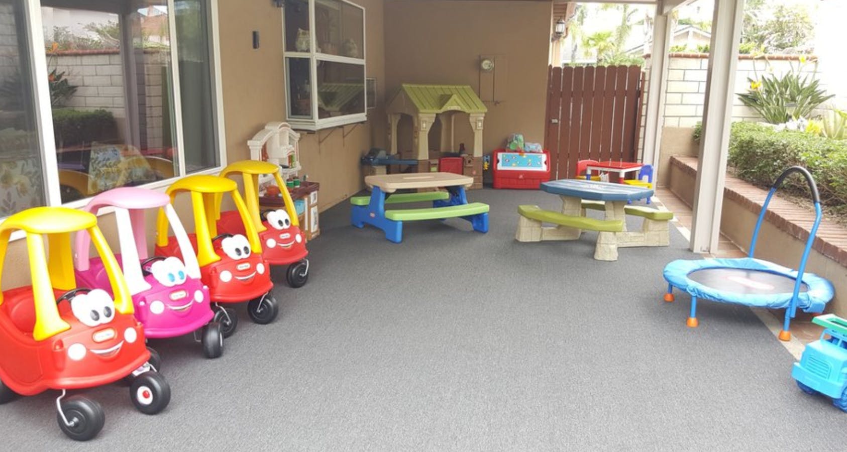 Four toy cars and playground equipment on a patio