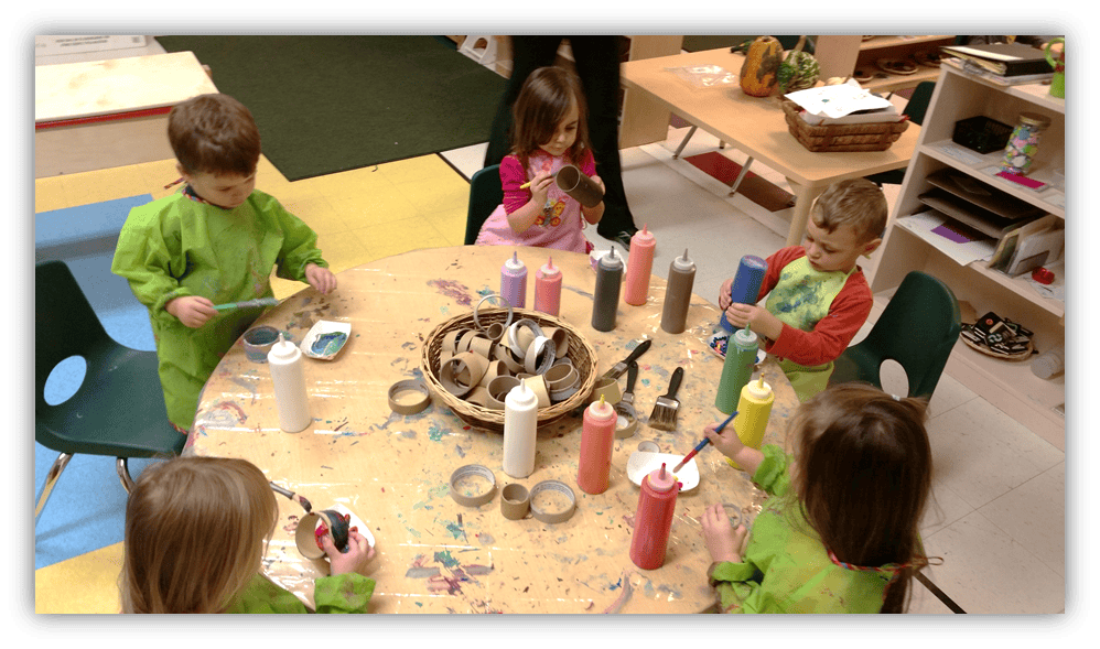 Children painting at a table in a classroom