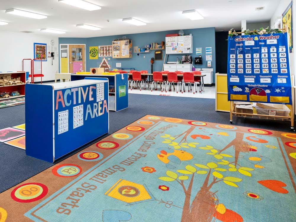 Classroom with child-sized furniture and a rug with a tree design