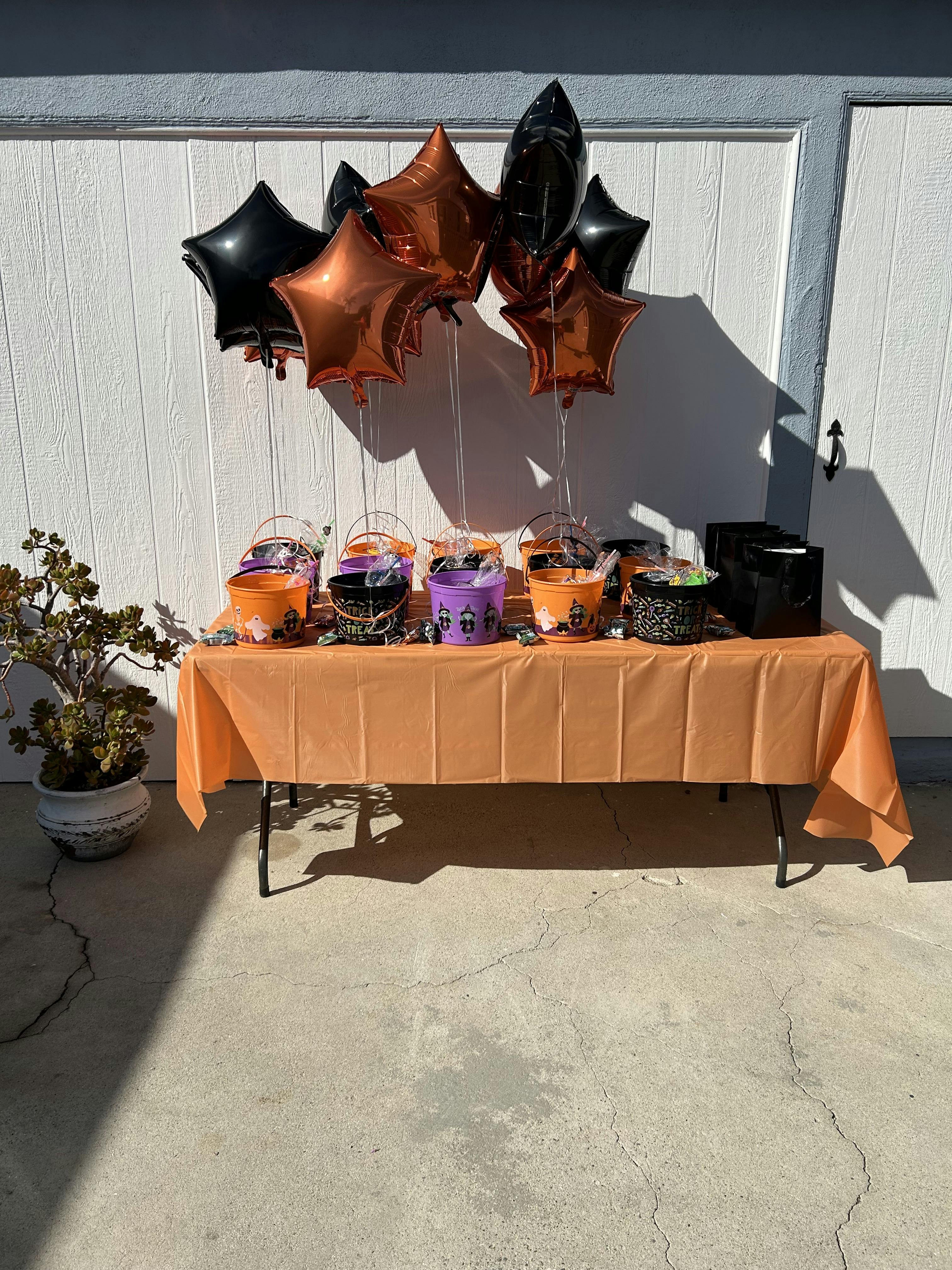 Table with orange tablecloth, Halloween buckets, and star-shaped balloons