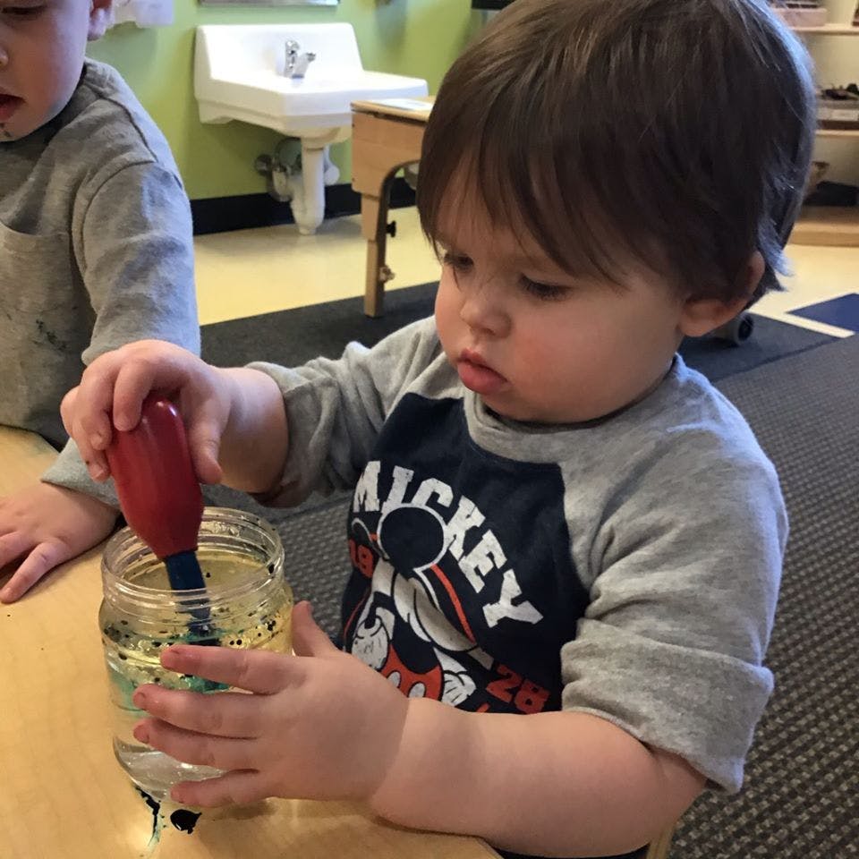 Child using a dropper in a jar of liquid