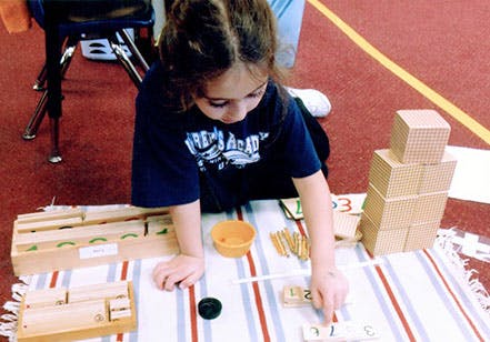 Child playing with wooden blocks and learning materials on a striped mat