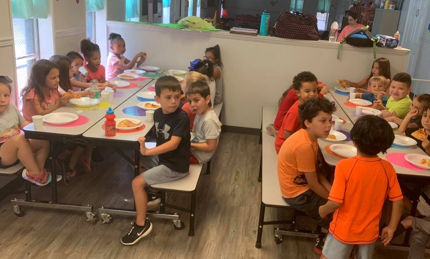 Children sitting at tables with plates