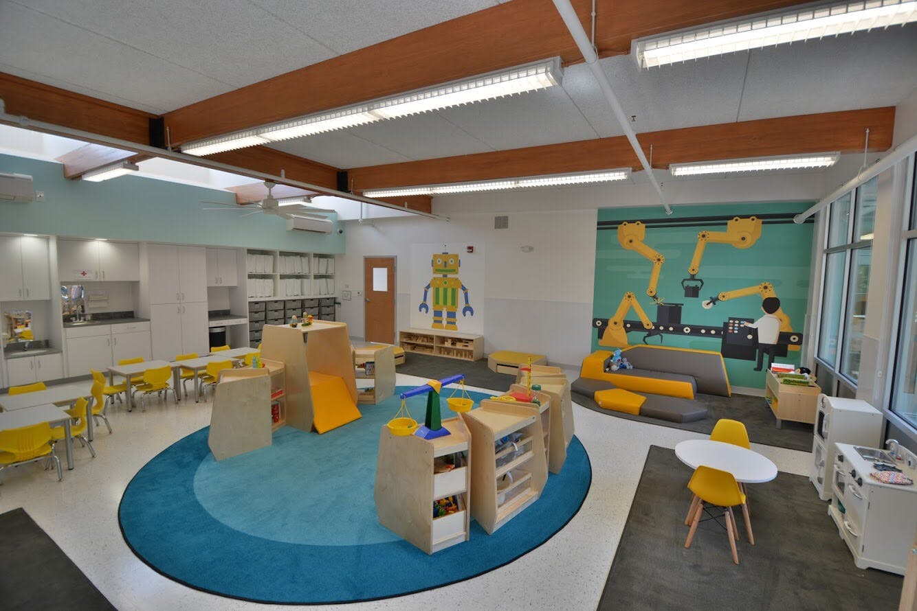 Playroom with blue rug, play structures, and yellow chairs
