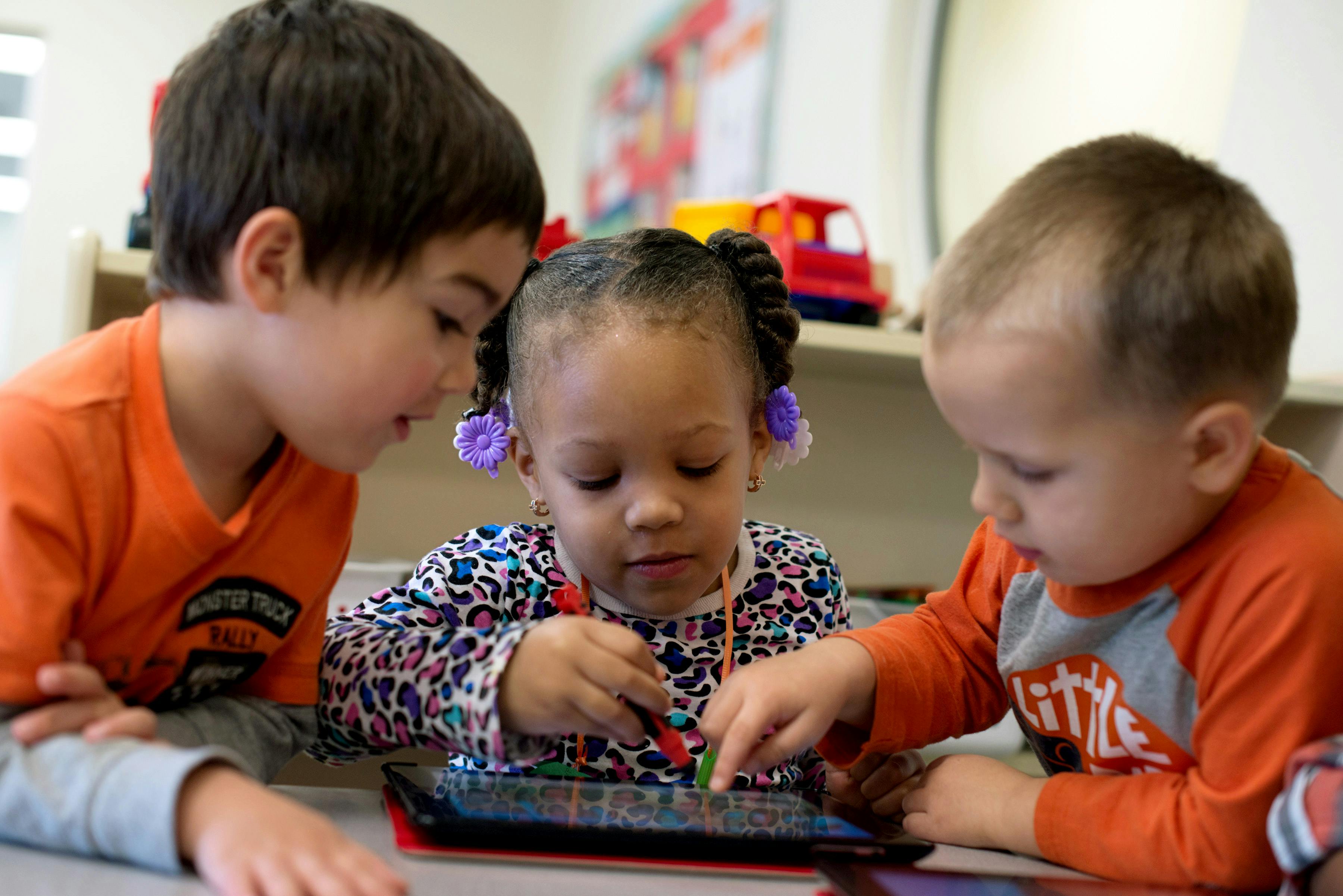 Three children looking at and touching a tablet