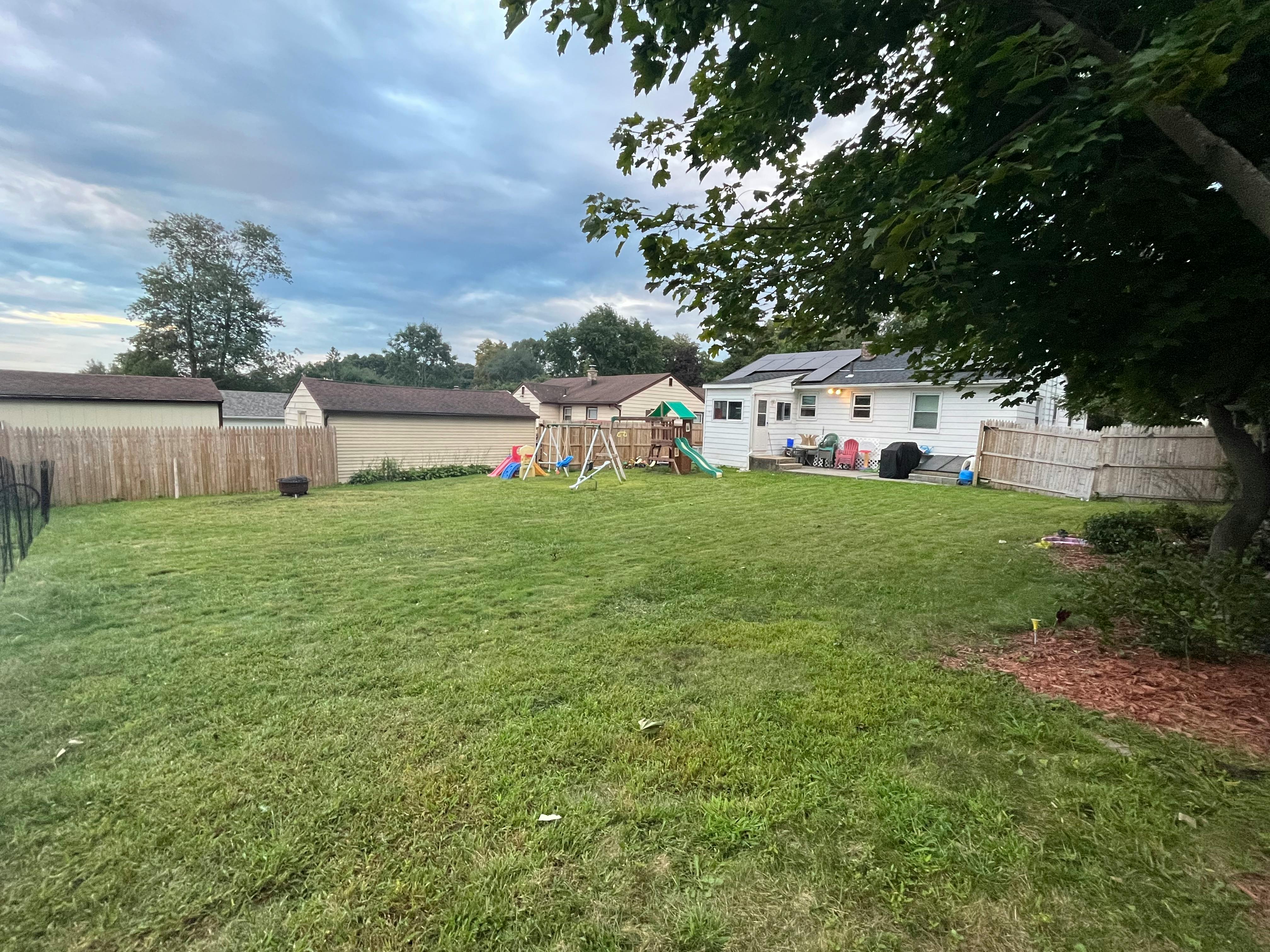 Grassy backyard with a wooden fence and a playset