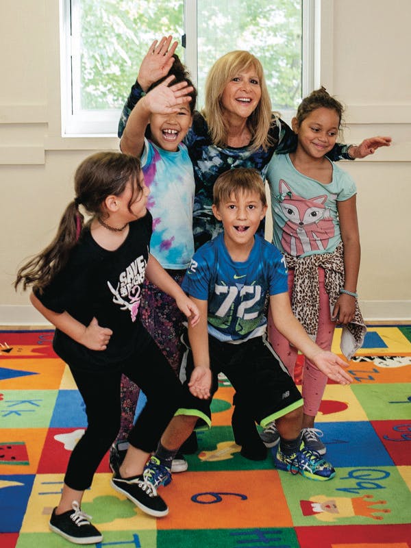 Adult and four children posing and waving